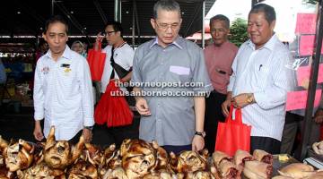 TINJAU: Fadillah (tengah) bersama Nogeh dan Paza (kiri) melawat tapak jualan khas pra-Syawal di Medan Niaga Satok semalam.