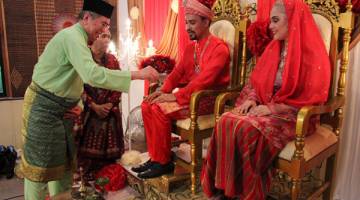 SEPADAN: Junaidi (kiri) merenjis pasangan pengantin olok-olok bagi menghidupkan budaya Melayu pada Majlis Indahnya Raya Homestay Kampung Santubong. 