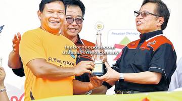 TAHNIAH: Abang Johari menyampaikan Piala Kontinjen Terbaik kepada Ketua Kontinjen Olahraga Sarawak, Watson Nyambek disaksikan Abdul Karim di Kuching semalam.