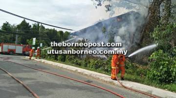 TERBAKAR: Anggota bomba melakukan operasi pemadaman api yang memusnahkan bekas pejabat Yayasan Sabah.