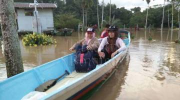 PANTAU: Para guru SK Kuala Sigu terpaksa menggunakan perahu bagi bergerak ke satu-satu tempat di kawasan sekolah ekoran dinaiki air sedalam sejak semalam.