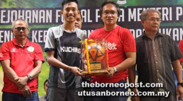 PEMAIN TERBAIK: Radzi (dua kanan) menyampaikan anugerah khas kepada pemain Kuching, Muhd Erzuan.