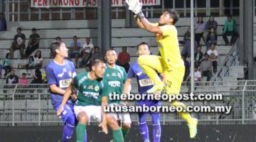 SENGIT: Penjaga gol UKM FC, Abdul Gapur Samsudin tangkas menyelamatkan gawang pasukannya dari ancaman penyerang Kuching FA (jersi hijau).