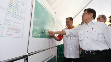 PROJEK PEMBANGUNAN: Abang Johari melihat pelan pembangunan bagi projek pembangunan perumahan di Kampung Sungai Bedaun, Jalan Sultan Tengah di Kuching hari ini. Turut kelihatan Ismail (kiri).