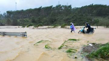 DIBADAI: Penduduk meredah banjir yang menenggelami lebuh raya di wilayah tengah Dak Lak susulan kemaraan Taufan Damrey kelmarin. — Gambar AFP