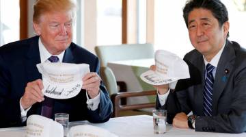 SAHABAT BAIK: Trump dan Abe menunjukkan topi yang telah ditandatangani dengan slogan ‘Donald dan Shinzo Menjadikan Pakatan Lebih Hebat’, sebelum makan tengah hari dan bermain golf di Kelab Golf Kasumigaseki di Kawagoe, semalam. — Gambar Reuters