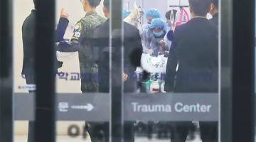 KRITIKAL: Seorang pegawai tentera Korea Selatan (dua kiri) memerhatikan anggota perubatan merawat seseorang yang dipercayai askar Utara yang berpaling tadah, di sebuah hospital di Suwon, selatan Seoul kelmarin. — Gambar AFP