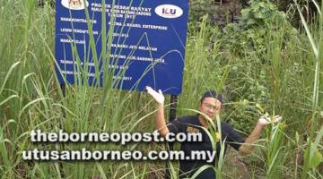 MANA PROJEK: Afiq menunjukkan papan tanda projek Jeti Kampung Jaie, Sadong Jaya dan di belakangnya jelas kelihatan jeti konkrit telah siap dibina.