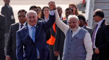 TETAP MESRA: Netanyahu (kiri) dan Modi mengangkat tangan selepas perdana menteri Israel itu tiba di lapangan terbang New Delhi, India, kelmarin. — Gambar Reuters