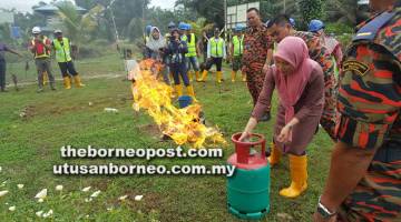 FOKUS: Salah seorang peserta diajar cara memadam tong gas yang menyembur api akibat hos tercabut.