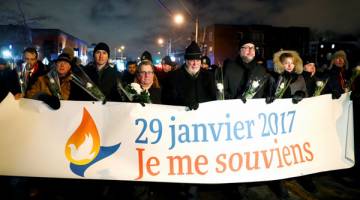 TENTANG ISLAMOFOBIA: Trudeau dan Perdana Menteri Quebec Philippe Couillard memegang kain rentang ketika menyertai                 perarakan sebagai tanda sokongan kepada masyarakat Islam dekat Pusat Kebudayaan Islam di Quebec, kelmarin. — Gambar Reuters