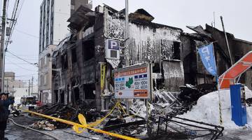 MUSNAH: Gambar serahan Kyodo menunjukkan anggota bomba memeriksa bangunan musnah dalam kebakaran yang mengorbankan 11 warga emas di Sapporo, Jepun semalam. — Gambar AFP/Reuters