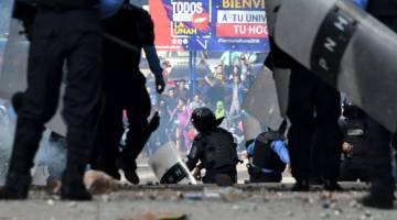 HURU-HARA: Polis bertempur dengan pelajar Universiti Autonomi Kebangsaan Honduras yang membantah pelantikan semula Hernandez sebagai presiden di Tegucigalpa kelmarin. — Gambar AFP