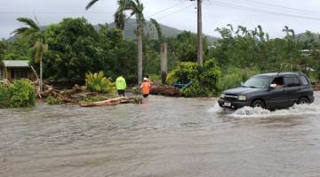 DIBADAI GITA: Gambar serahan Palang Merah Samoa semalam menunjukkan sebuah kereta meredah jalan yang ditenggelami air ketika para pekerja bantuan memeriksa sebuah rumah di kawasan Apia. — Gambar AFP