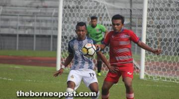 KAWAL KETAT: Penjaring gol pertama Kuching FA, Ahmad (kiri) dikawal ketat pertahanan Real Chukai FC pada perlawanan Piala FA 2018 di Stadium Negeri, Petra Jaya Kuching semalam.