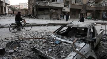 AKIBAT BOM: Penduduk Syria berjalan melalui jalan yang dipenuhi runtuhan selepas pengeboman di Arbin di wilayah Ghouta Timur yang ditawan oleh pemberontak pada 25 Februari. — Gambar AFP