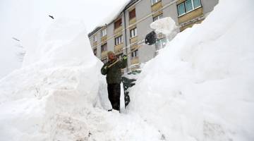 DINGIN: Seorang lelaki mengalihkan salji di hadapan sebuah bangunan di Delnice, Croatia kelmarin. — Gambar Reuters