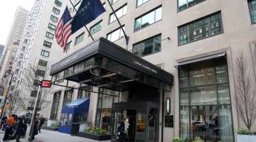 KENA SERBU: Pejalan kaki melintasi Hotel Loews Regency di New York kelmarin selepas FBI menyerbu pejabat dan bilik peguam peribadi Trump di hotel tersebut. — Gambar AFP