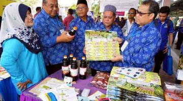 TERTARIK: Abdul Fattah (kanan) melihat produk jualan anggota koperasi selepas merasmikan Majlis Persidangan ANGKASA Negeri Kedah di MRSM Merbok, semalam. — Gambar Bernama