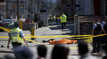 MALANG: Mayat mangsa ditutup dengan kain tarpal selepas pemandu van merempuh pejalan kaki di Toronto kelmarin. — Gambar AFP