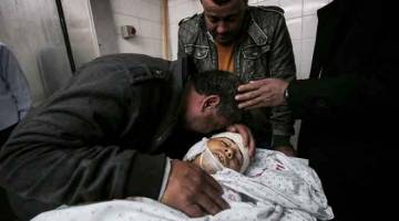 SYAHID: Saudara mara Oweida meratap di sisi jenazahnya di rumah mayat di hospital di Khan Yunis di selatan Gaza semalam. — Gambar AFP