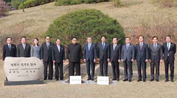 BERSATU: Kim (enam kanan) dan Moon (tujuh kanan) turut serta dalam majlis penanaman pokok bersebelahan dengan Garisan Pembatasan Ketenteraan yang membentuk dua sempadan Korea di kampung kedamaian sementara Panmunjom. — Gambar AFP