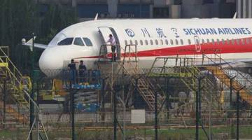 PERIKSA: Pekerja memeriksa pesawat Sichuan Airlines yang membuat pendaratan kecemasan selepas cermin depan kokpit tercabut, di lapangan terbang di Chengdu, wilayah Sichuan, China kelmarin. — Gambar Reuters