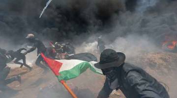 INTIFADA: Pembantah Palestin melarikan diri dari gas pemedih mata ketika membantah pembukaan kedutaan AS di Baitulmuqaddis, di selatan Semenanjung Gaza kelmarin. — Gambar Reuters