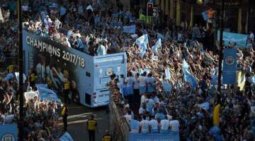 MUSIM HEBAT: Para pemain dan pegawai pasukan menaiki bas terbuka disambut oleh ribuan para penyokong City yang membanjiri di jalan-jalan di kota Manchester untuk meraikan kejayaan mereka menjuarai Liga Perdana Inggeris. — Gambar Reuters
