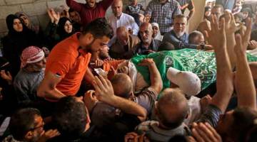 SYAHID: Penduduk Palestin mengusung jenazah Nasser Ghorab, 51, semasa upacara pengebumiannya di kem pelarian al-Nusirat di tengah semenanjung Gaza kelmarin selepas beliau terbunuh sehari sebelumnya dalam pertempuran dengan tentera Israel di sempadan Gaza. — Gambar AFP