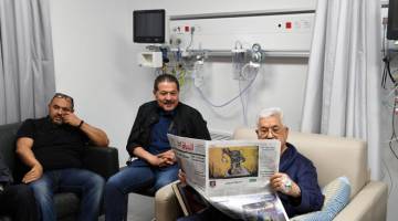 SEMAKIN BAIK: Gambar serahan Pejabat Presiden Palestin (PPO) menunjukkan Abbas membaca surat khabar di hospital di Ramallah, di wilayah Tebing Barat, kelmarin. — Gambar Reuters