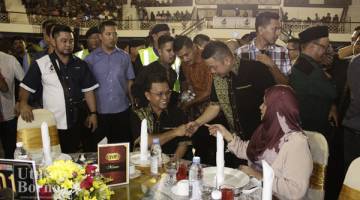 SHAFIE (duduk, kiri) bersalaman dengan Darell ketika di majlis itu.