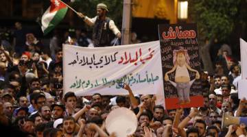 KAMI BANTAH!: Penunjuk perasaan menjulang poster ketika membantah draf undang-undang cukai yang kontroversi dalam                  perhimpunan raksasa berhampiran pejabat perdana menteri di Amman, Jordan semalam. — Gambar AFP