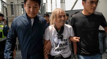 CUBAAN GAGAL: Robert (tengah) ditangkap selepas dihalang                          di tengah-tengah cubaannya untuk mendaki Menara Dunia Lotte di Seoul, Korea Selatan semalam. — Gambar AFP