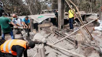 TERUS GELEDAH: Anggota penyelamat dan penduduk menggeledah serpihan untuk mencari mangsa di kawasan terjejas oleh letusan gunung berapi Fuego di kampung San Miguel Los Lotes, bahagian Escuintla, Guatemala kelmarin. — Gambar Reuters 