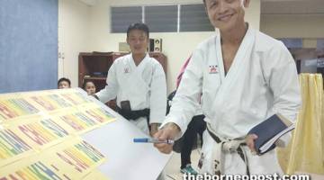 JULIAN menandatangi papan iklan sebagai perasmi kelab Karate SK Telupid.