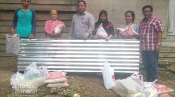  ASMAD (tiga kiri) bersama Abdullah Ghani (kanan) menyerahkan sumbangan bahan makanan mentah kepada keluarga Rahimah dan Siti Nurhaya yang menjadi mangsa beranda ranap akibat dihempap okok kelapa sawit tumbang di Kg Kolapis Darat Beluran.