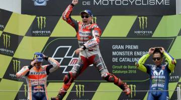 LOMPAT TINGGI: Lorenzo (tengah) meraikan kejayaan selepas memenangi tempat pertama dalam MotoGP Catalunya sambil disaksikan Marquez (kiri) dan Rossi di Litar Montmelo. — Gambar AFP