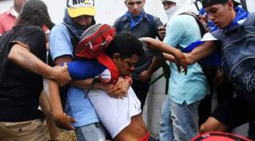 PERTUMPAHAN DARAH: Seorang penunjuk perasaan antikerajaan dibantu rakan-rakan yang lain setelah mengalami kecederaan semasa menyertai Marcha de las Flores di Managua, kelmarin. — Gambar AFP