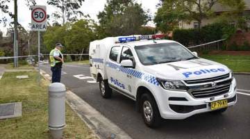 TRAGIS: Anggota polis dilihat berkawal di jalan masuk ke kediaman di mana seorang lelaki menembak mati dua anak remajanya sebelum membunuh dirinya sendiri di Sydney, Australia semalam. — Gambar AFP