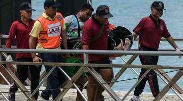 MALANG: Anggota penyelamat Thai mengangkat mayat pelancong yang mati lemas selepas                     sebuah bot karam di luar pantai pulau peranginan Phuket, Thailand, semalam. — Gambar AFP