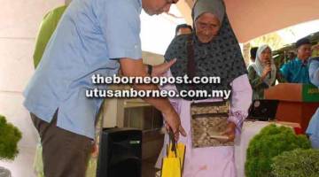 BANTUAN: Azis menyampaikan sumbangan kepada ibu tunggal yang diraikan pada perjumpaan dengan warga RELA di Pusat Latihan RELA Sabah.
