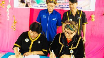 EWON (kiri) menyaksikan acara menandatangani persefahaman antara SK Taginambur yang diwakili Betty (duduk kiri) dan Simbih.