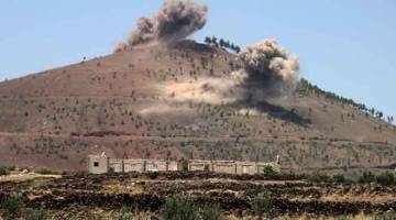 MASIH BERPERANG: Asap berkepul dari kawasan bukit-bukau di bandar selatan al-Harah, tenggara Quneitra, semasa tentera kerajaan melancarkan serangan kelmarin. — Gambar AFP