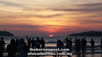 SUASANA pengunjung merakamkan detik matahari terbenam di Pantai Tanjung Aru.