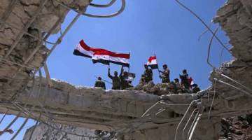 TAWAN SEMULA: Tentera kerajaan Syria mengayunkan bendera kebangsaan mereka selepas menawan semula bandar Quneitra daripada pemberontak kelmarin. — Gambar AFP