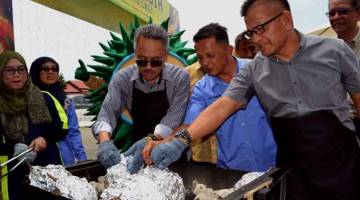 ENAK: Norhizam (kanan) dan Ahmad Ishak (dua kiri) membakar durian pada Karnival ‘Melaka Durian Street’, pada majlis karnival berkenaan di Pusat Dagangan Antarabangsa Melaka. — Gambar Bernama