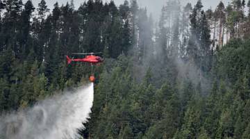 PADAM API: Helikopter mencurahkan air ke atas kebakaran hutan dekat kampung Grotingen di tengah Sweden. — Gambar Reuters