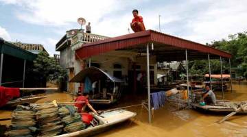BANJIR: Seorang lelaki duduk di atas bumbung rumahnya selepas banjir melanda wilayah Ninh Binh kelmarin. — Gambar Reuters 
