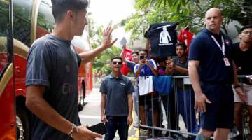 MESRA: Ozil melambai ke arah penyokong Arsenal sebaik tiba di hotel penginapan pasukannya selepas menjalani latihan di Singapura semalam. — Gambar Reuters